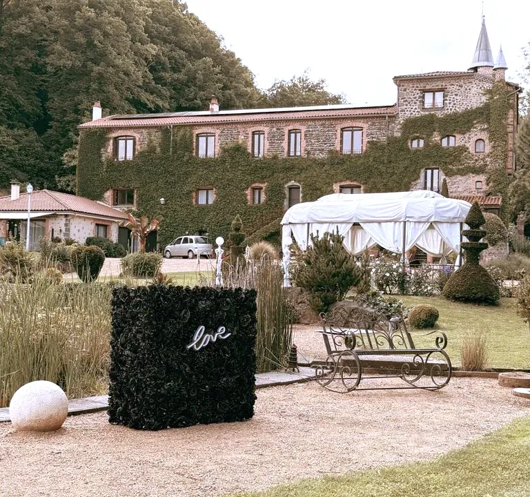 Le stand habillé de fleurs noires, avec son néon « love », sur le gravier, devant un château couvert de lierre
